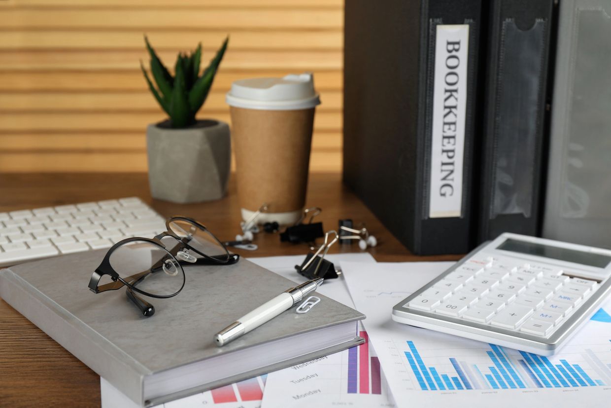 Office desk with bookkeeping files, calculator, and glasses.