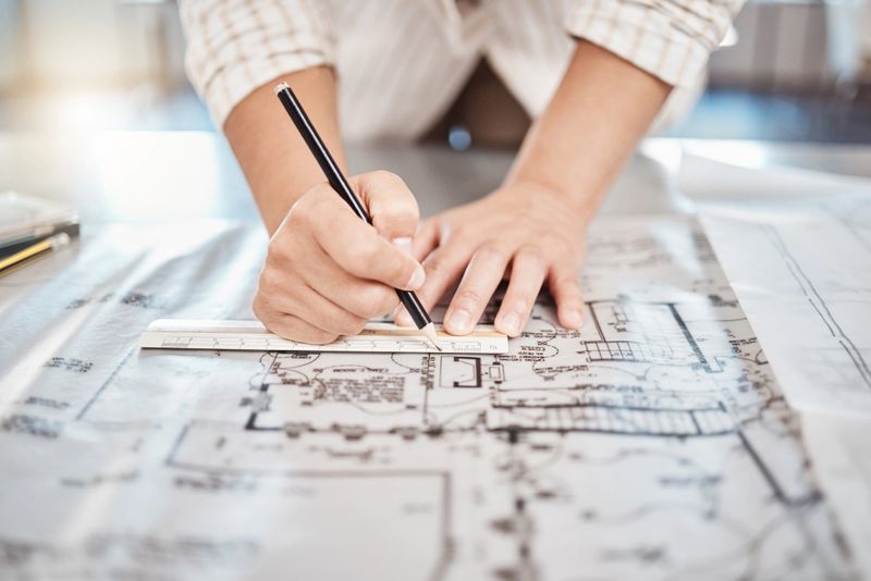 Architect drawing building floor plan, design blueprint map and engineer drafting structure on table paper. Real estate development work, house office construction and industrial wall safety ruler
