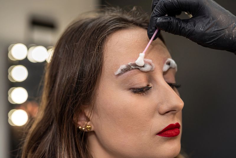 lashmaker applied eyebrow lamination foam to the client's eyebrows. eyebrow concept. painting and lamination