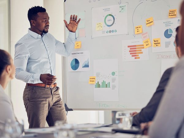 Man presenting marketing data and charts to colleagues in a meeting.