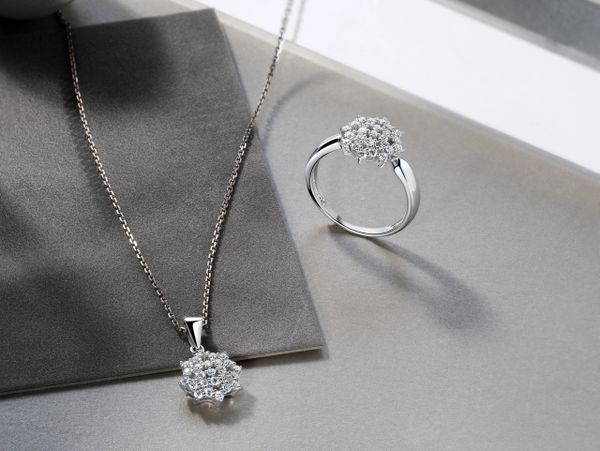 Elegant silver necklace and ring set with sparkling diamond clusters.