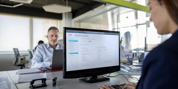 Two people working in a modern office with computer screens and documents.