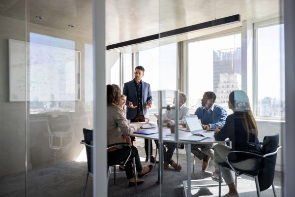 Business team engaged in a meeting in a modern glass-walled office.
