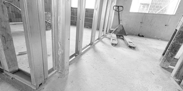 Interior view of a building under construction with metal framing and a pallet jack.