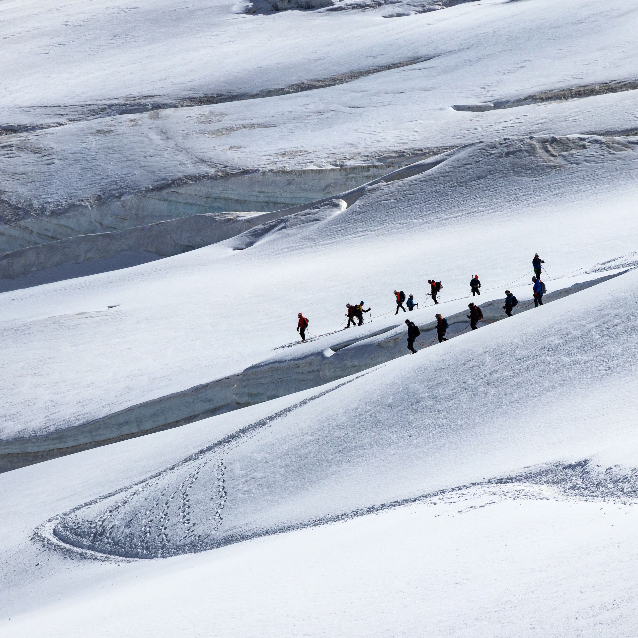 Group of climbers crossing a snowy mountain glacier.