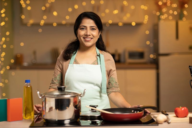 Portrait of Indian woman enjoying while cooking meal in the kitchen
