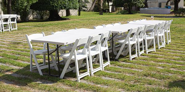 Outdoor white tables and chairs on grass.