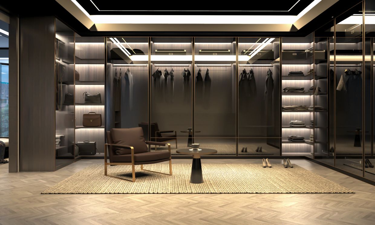 Luxurious modern walk-in closet with glass doors and seating area.