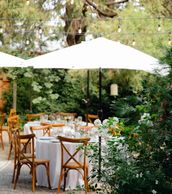 Elegant outdoor dining setup with wooden chairs and white umbrellas.