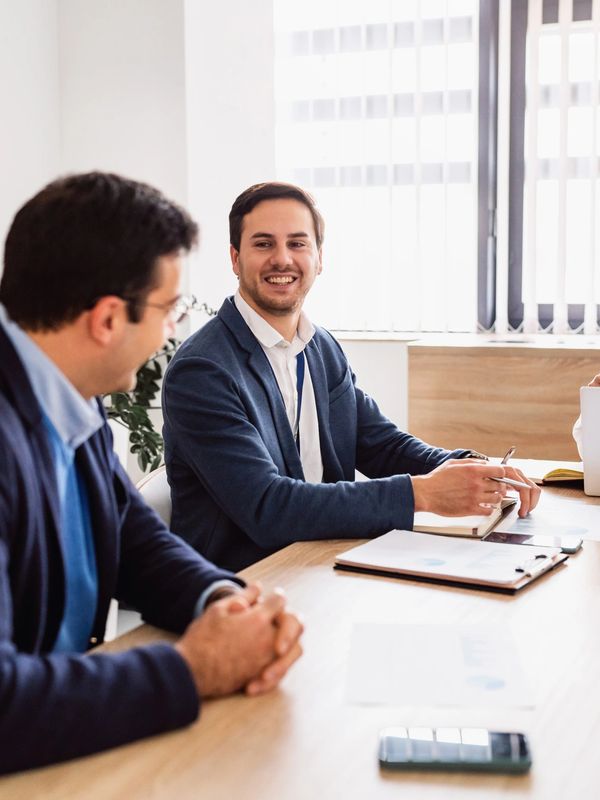 Two men in business attire smiling during a meeting.