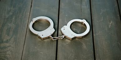 Metal handcuffs lying open on a wooden surface.