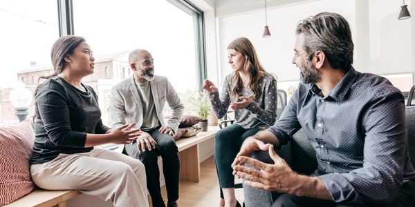 Four people engaged in an animated discussion in a bright office.