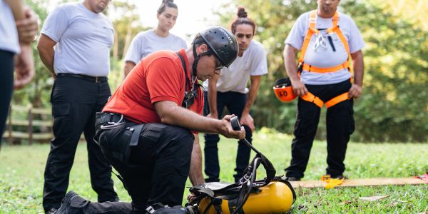 Instructor demonstrating safety gear to a group outdoors.