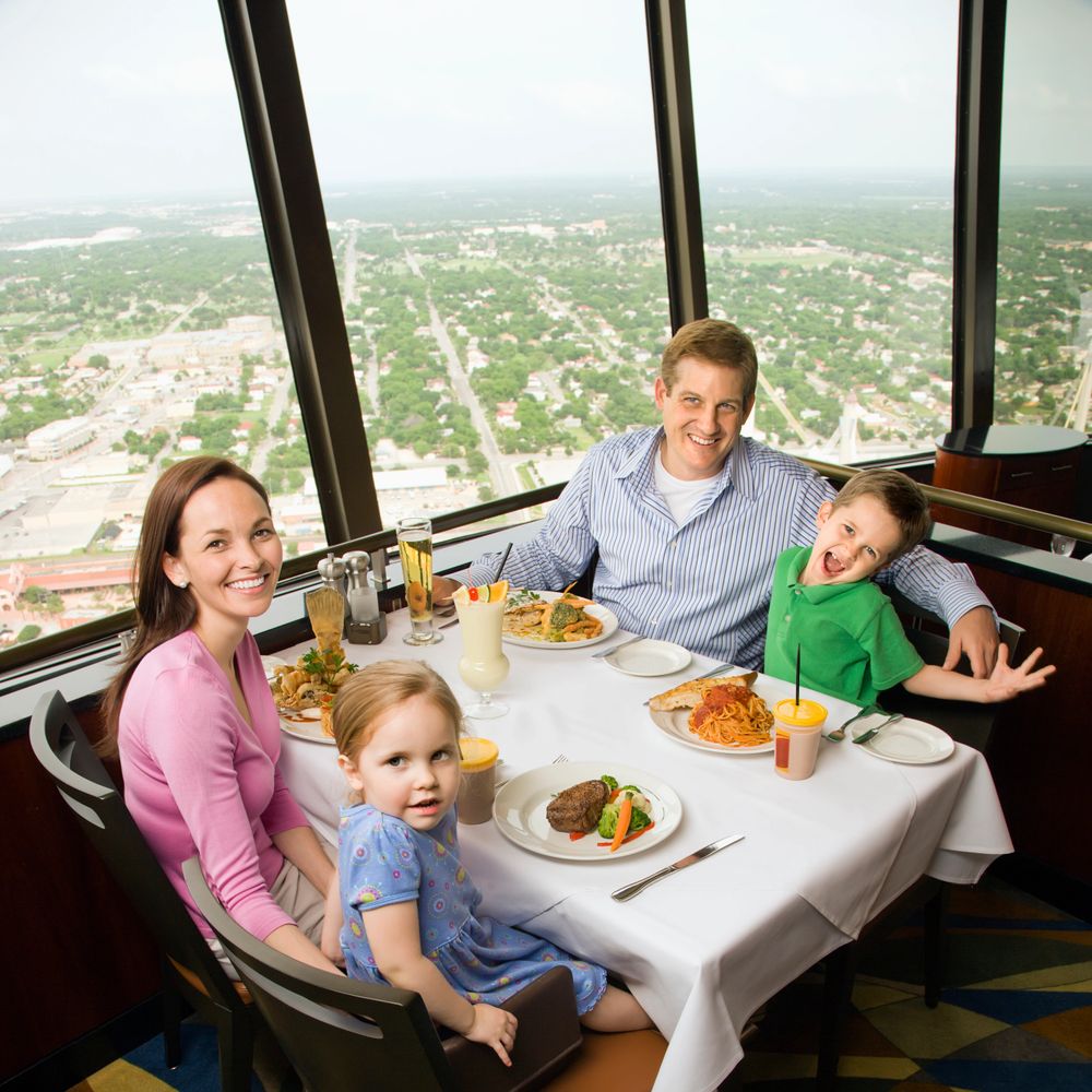 Family enjoying a meal with a city view from a high-rise restaurant.