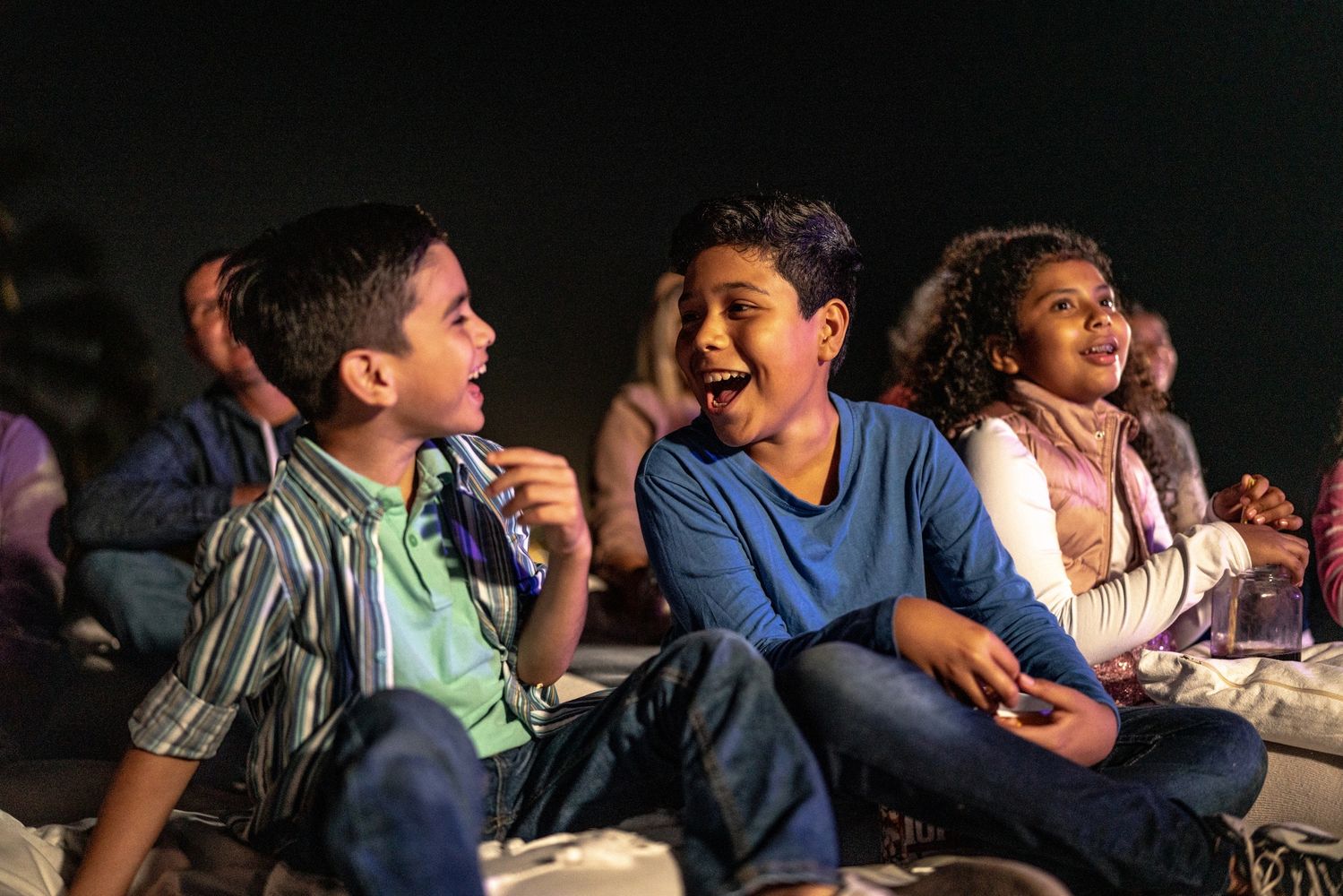 Children laughing and enjoying a nighttime outdoor event together.