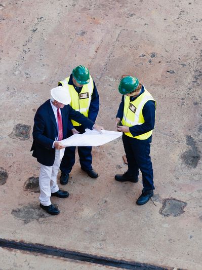 Overhead view of three construction workers reviewing plans.