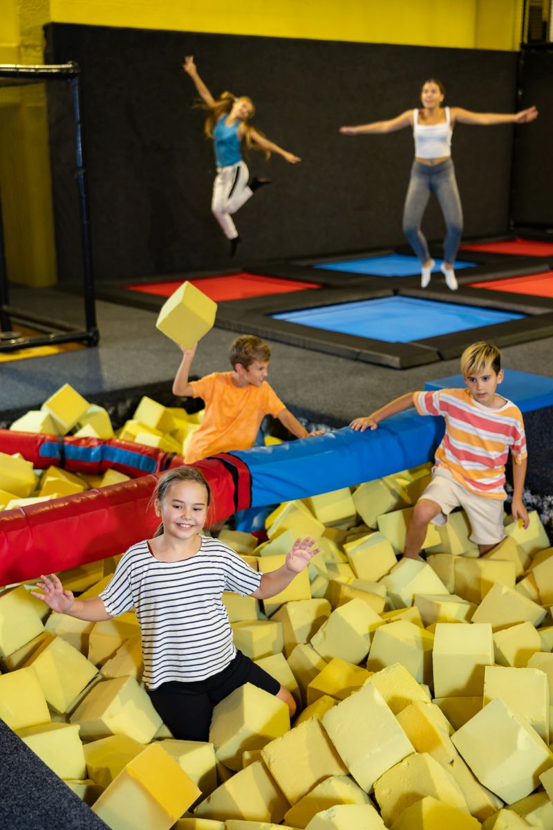 Group of excited active children having fun while playing and jumping in soft cubes in the dry pool of the game room for birthday