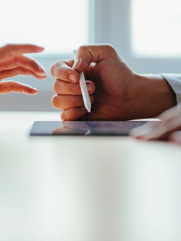 Two people interacting with a tablet and stylus on a table.