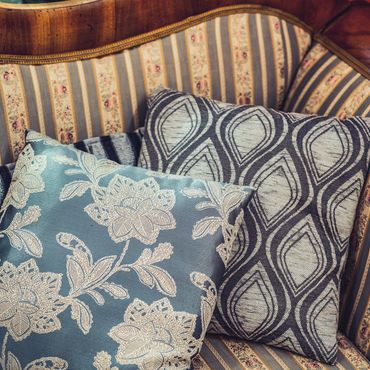 Two patterned decorative pillows on a striped vintage sofa.