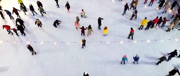 A group of young people posing on an ice rink, wearing red jackets.