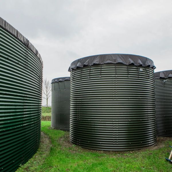 Large black cylindrical tanks covered with tarps outdoors.