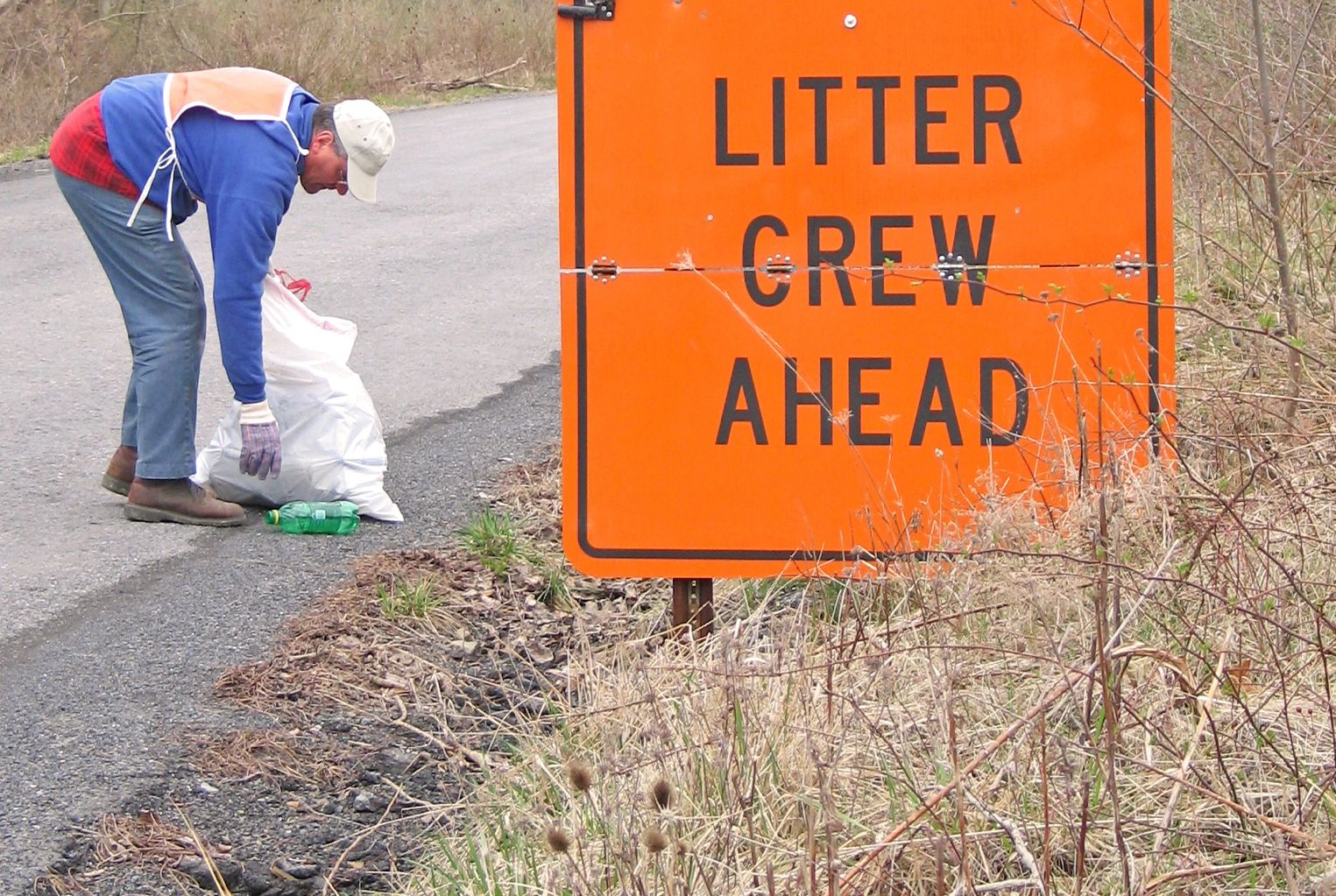 A man cleaning the side of the highway.