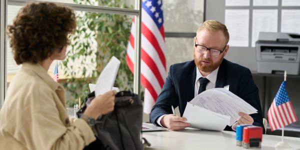 Man and woman discussing documents at a desk with American flags.