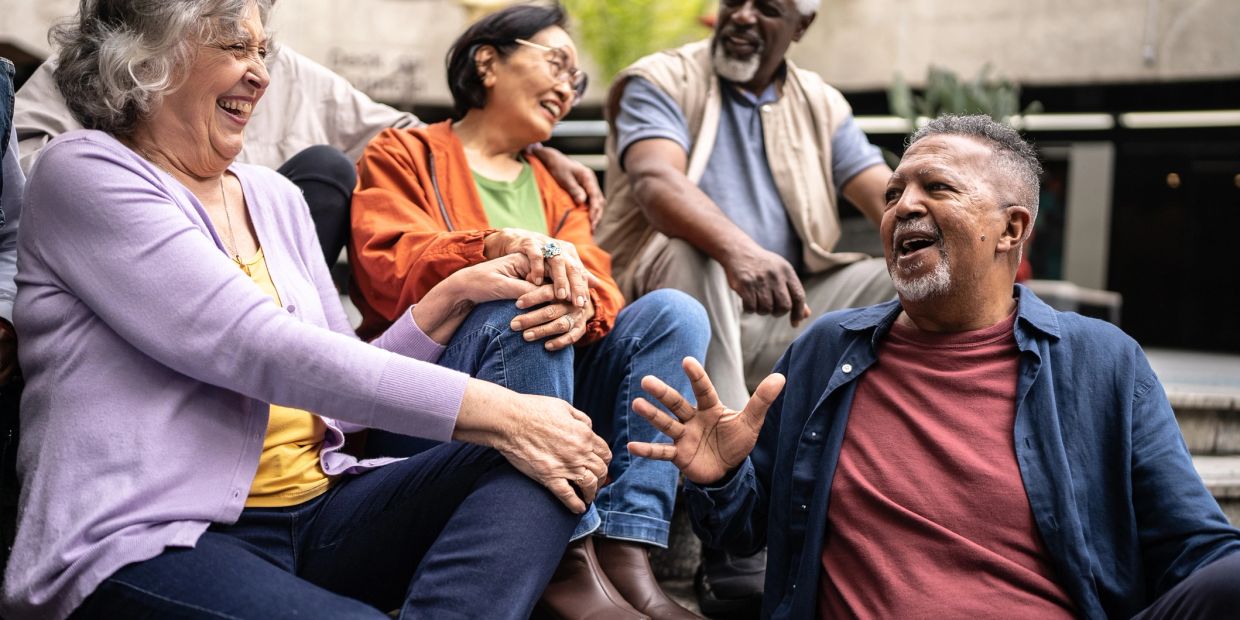 Group of elderly friends laughing outdoors.