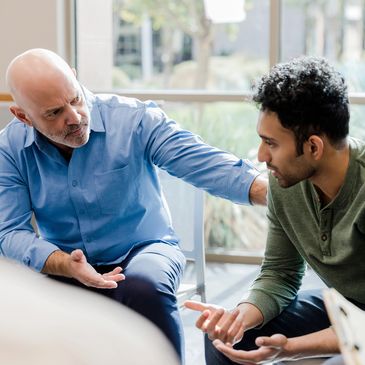 Two men engaged in a serious conversation, one comforting the other.