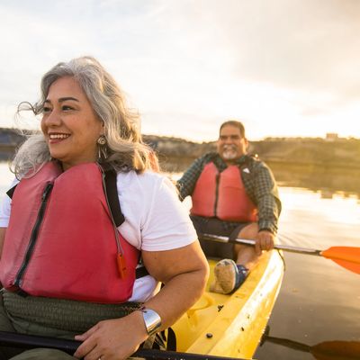 Smiling couple kayaking together on calm water at sunset.