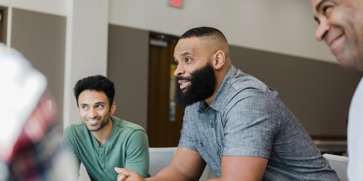 Three men engaged in a discussion indoors.