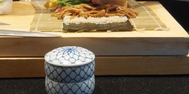Cup of tea next to sushi on a wooden serving board.