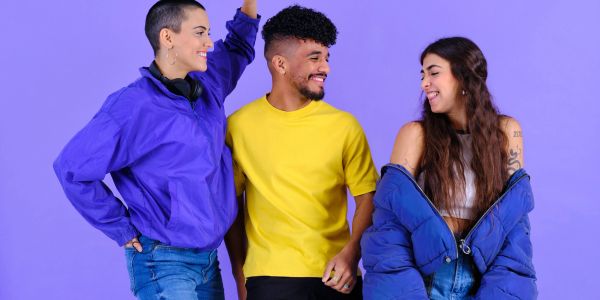 Three friends smiling and chatting against a purple background.