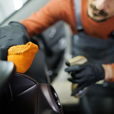 Person cleaning car interior with orange cloth.