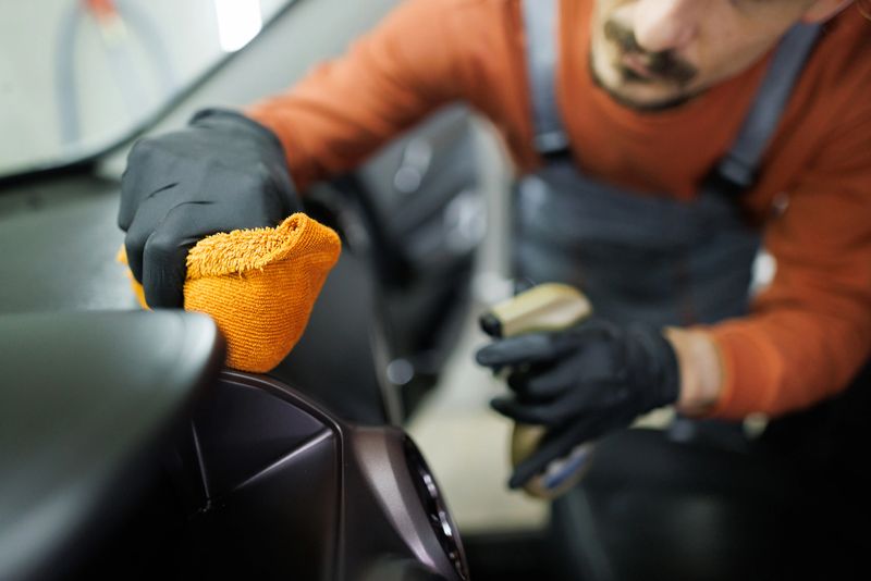 Close up shot of professional car detailer cleaning car interior with a microfiber towerl