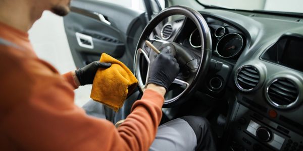 Person cleaning a car's steering wheel.
