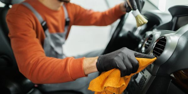 Person cleaning a car's dashboard with a cloth.