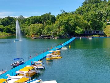 Scenic lake with floating yellow pedal boats and a blue floating walkway.