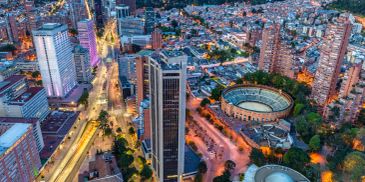 Aerial evening view of a city with tall buildings and a circular stadium.