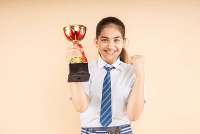 Girl in school uniform holding a trophy and celebrating.