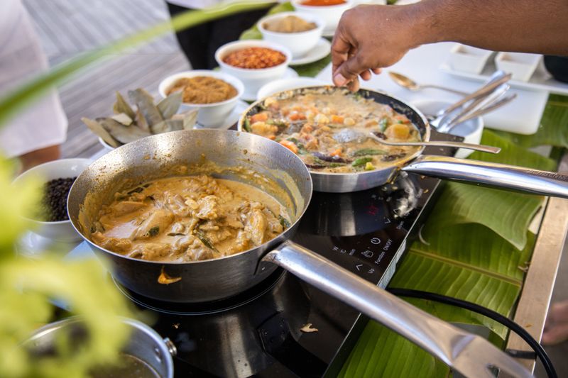 Cooking Maldivian Tuna Curry in steel pan at kitchen with coconut cream milk and spices