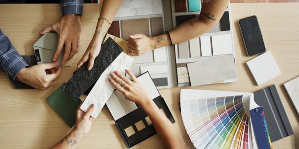 People collaborating over color swatches and material samples on a wooden table.