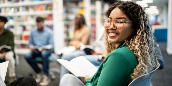 Young woman smiling with a book in a group reading session.