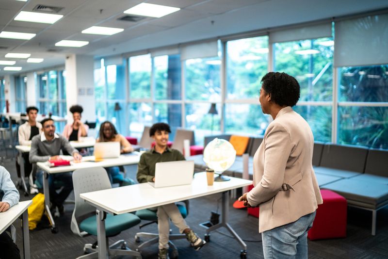 Mature teacher woman talking to students during class at university