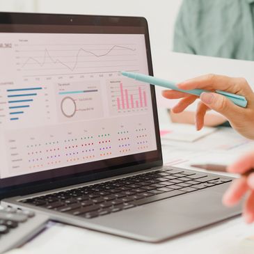 Two people analyzing financial data on a laptop screen with charts and graphs.