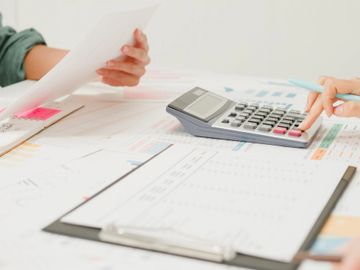 People using a calculator and reviewing documents at a desk.