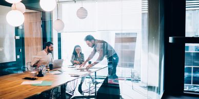 Three colleagues collaborating in a modern office meeting room with bright lighting.
