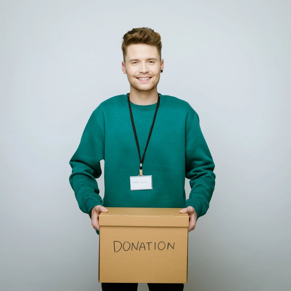 Smiling man holding a donation box, ready to help.
