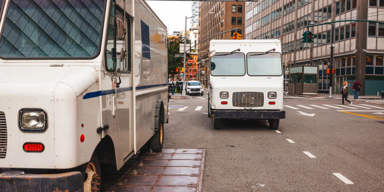 Two white delivery trucks on a city street.
