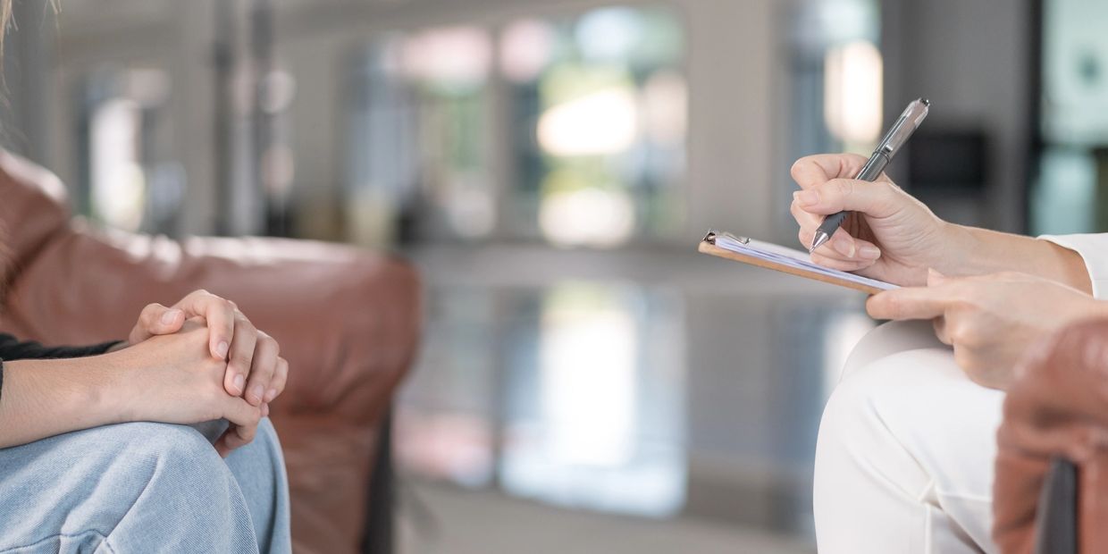 Person consulting with a licensed clinical psychologist taking notes on a clipboard. The psychologist is bilingual in Spanish and English. 